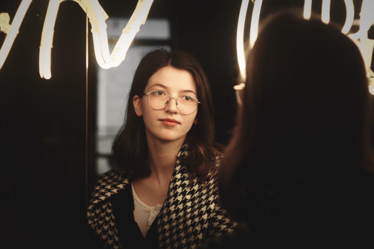 young woman gazing seriously into a mirror